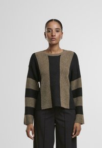 Sweter dzianinowy w poziome paski w ciemnym brązie, beżu i czerni. Posiada okrągły dekolt i szerokie rękawy. Teksturowany materiał.