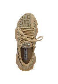 Baskets de sport beiges avec une tige en maille texturée, motif subtil, accents dorés et épaisse semelle transparente. Les lacets sont noués et la languette affiche le logo.