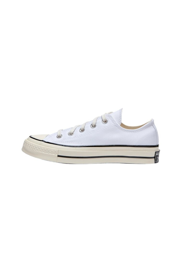 Vita segel-sneakers med låg topp, rund tå, svart rand längs sulan och fem snörhål. Har en texturerad gummitå och hälslits.
