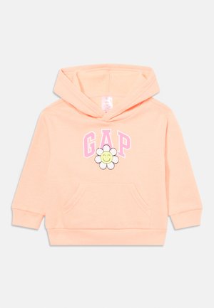 Hoodie rose clair avec une poche frontale, arborant "GAP" en rose et un graphique de marguerite souriante au centre. Matière en coton douce.
