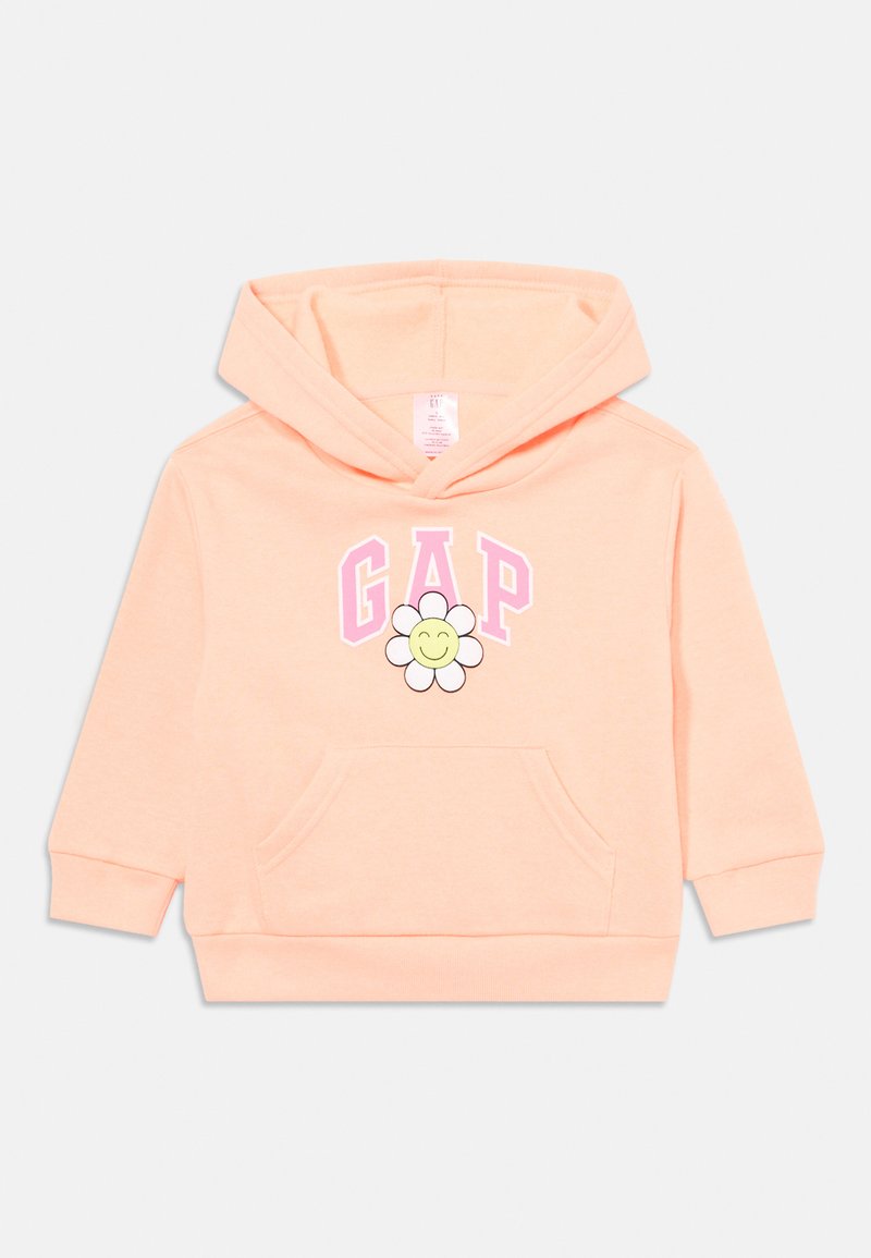 Hoodie cor pêssego com um bolso frontal, apresentando "GAP" em rosa e um gráfico de margarida sorridente ao centro. Material de algodão suave.