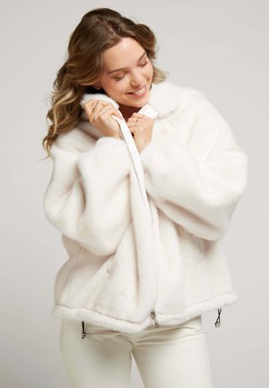 Veste en fausse fourrure blanche avec capuche, à forme oversized, dotée d'une fermeture éclair à l'avant, de poches latérales et de accents à cordon de serrage au bas.