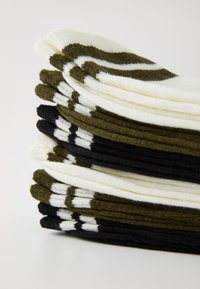 Stack of socks in white, olive green, and black. Each pair features a distinctive pattern. Made of soft, flexible material.