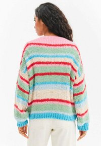 Sweter dziany w wielokolorowe paski; zawiera różowy, czerwony, zielony, niebieski oraz kremowy kolor. Luźny fason, prążkowane mankiety i detale na dole.