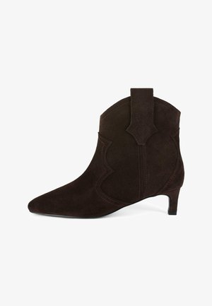 Stivale alla caviglia in suede marrone con punta allungata, ritagli decorativi, tacco corto e una linguetta sul retro. Presenta dettagli di cuciture a contrasto.
