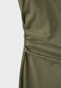 Tessuto verde oliva con dettaglio arricciato raccolto lungo una cucitura verticale su un capo di abbigliamento.