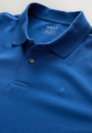 Polo azul hecho de una tela texturizada, con cuello, tapeta de dos botones y un logo bordado de un ciervo en el lado izquierdo del pecho.