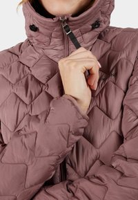 Kviltad jacka i dämpad mauve, med hög krage, dragkedjeslutning och elastiska ärmslut. Materialet ser mjukt ut med en slät textur.