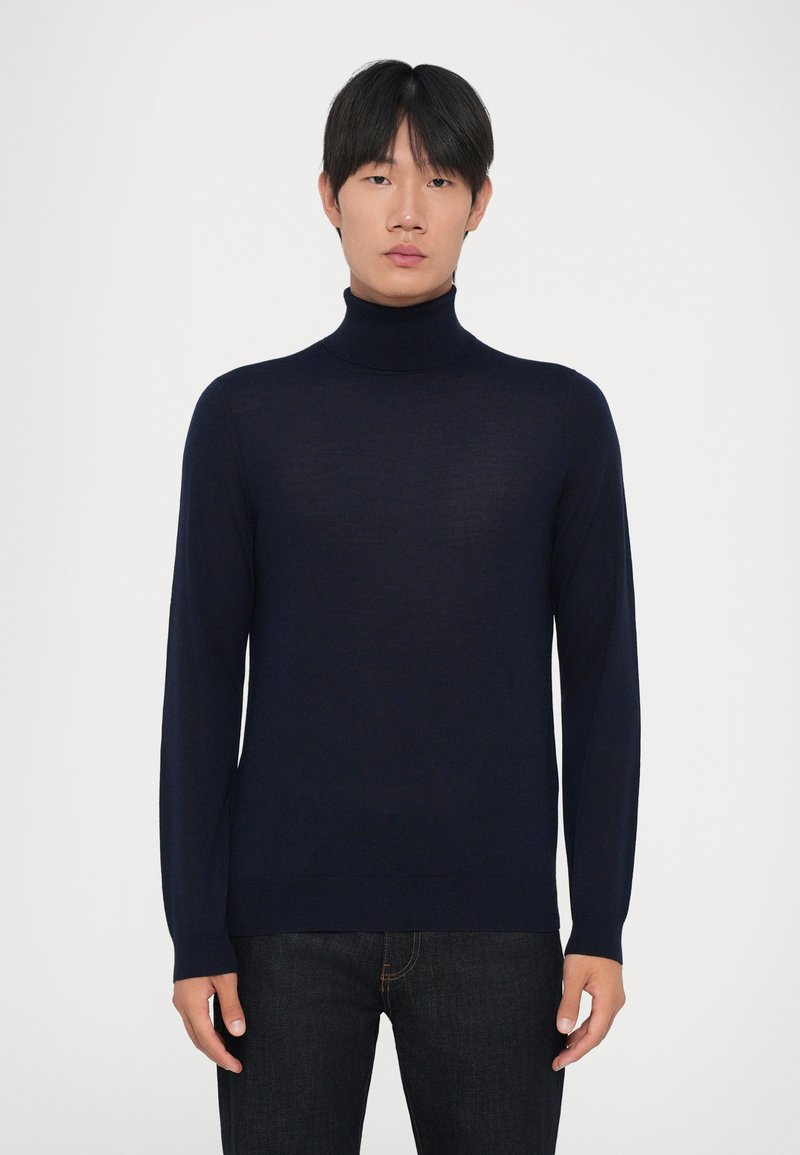 Navyblauer Rollkragenpullover aus leichtem Material, körperbetontes Design, lange Ärmel, gerippter Kragen und Saum, kombiniert mit dunklen Jeans.