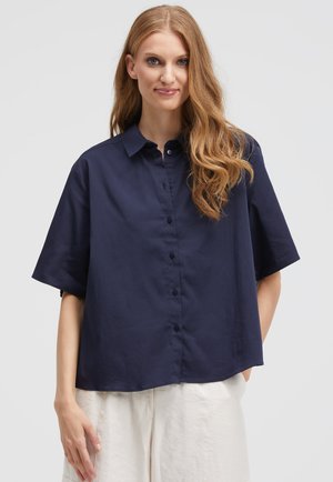 Navy blue short-sleeve shirt made of soft fabric, featuring a button front, spread collar, and a relaxed fit. Smooth texture and simple design.