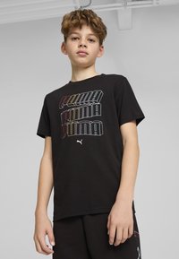Zwarte katoenen T-shirt met herhaalde "PUMA"-logo in kleurrijke, 3D-stijl typografie; korte mouwen, ronde hals en een ontspannen fit.