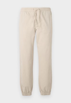 Pantaloni joggeri bej, ușori, cu talie elastică și șnur. Mansete adaptate la glezne, textură fină, design minimalist.