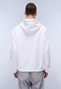 Felpa bianca con cappuccio dal fit rilassato. Presenta una tasca a marsupio, bordo e polsini a costine. Tessuto morbido al tatto, design minimalista.