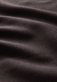 Gros plan d'un tissu côtelé gris foncé avec des plis doux et de fines lignes de texture verticale.