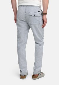 Slim-fit bomuldsbukser med et blåt og hvidt stribet mønster, udstyret med en baglomme med klap og knaplukning.