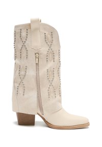 Botines beige con punta afilada, hechos de cuero y ante, con tachuelas decorativas y una cremallera lateral. Tacón grueso con aspecto de madera.