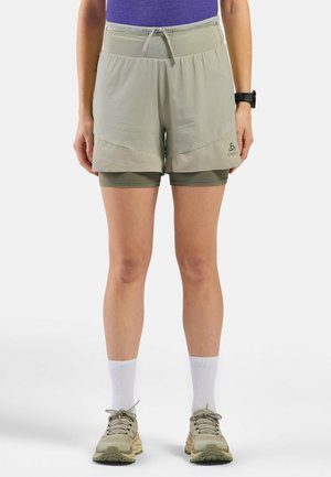 Hellgrüne Sportshorts mit integrierten Kompressionsshorts, elastischem Bund mit Kordelzug und strukturiertem Material. Sichtbares Logo-Detail an der Seite.