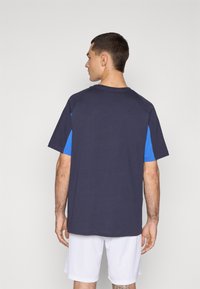 T-shirt met korte mouwen, featuring een marineblauw lichaam en levendige blauwe raglanmouwen, gemaakt van zachte stof met een relaxte pasvorm.
