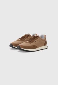 Brown synthetic sneakers with a white midsole, round toe, and black rubber outsole. Features laces and branding on the tongue.