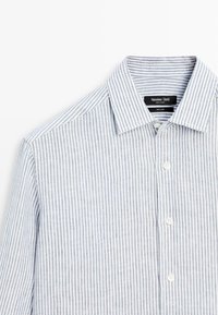 Camicia da uomo a maniche lunghe in lino, con bottoni, a righe verticali bianche e azzurro chiaro e colletto appuntito.