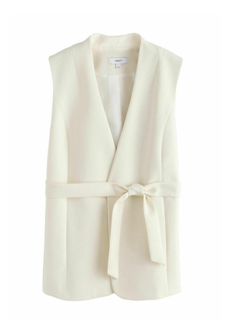 Cream sleeveless blazer with a V-neck, belted waist, smooth fabric, and a classic tailored shape. No visible buttons or hardware.
