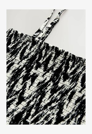Sort-hvidt mønstret stof med en krøllet tekstur, der har tynde stropper og en rynket topsektion.