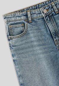 Jeans in denim azzurro chiaro con un design classico, dotati di una tasca frontale, bottone in ottone e cuciture arancioni sui bordi.