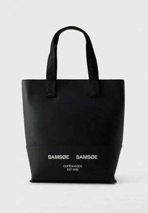 Sac cabas noir à deux anses avec le nom Samsøe Samsøe Copenhagen en blanc, sur un fond clair.