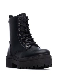 Botas de cuero negro con cordones hasta el tobillo, con una gruesa suela de plataforma texturada y ojales de metal. Presenta una lengüeta en el talón.