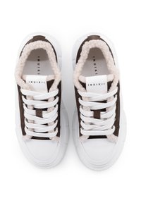 Sneakers in suede marrone con fodera in pelliccia bianca, suola in gomma bianca e lacci bianchi. Il design presenta un'estetica minimalista e un logo sulla linguetta.