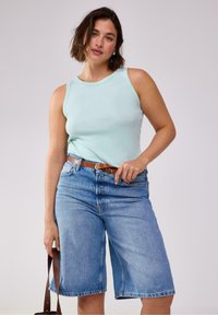 Lys blå ribbet tanktop, der er kombineret med lys blå denim bermuda shorts. En brun bælte fremhæver taljen. Enkel, afslappet outfitting.
