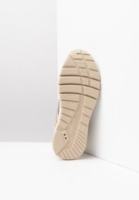 La semelle de la chaussure présente un design en caoutchouc beige texturé avec des motifs de traction, un détail de logo et un petit drapeau italien. La chaussure est inclinée sur un fond blanc.