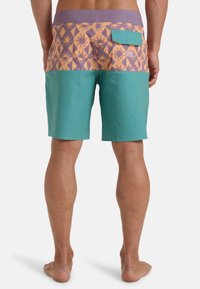 Plavky s pásom v oranžovej a purpurovej farbe so vzorom a jednofarebným tyrkysovým spodkom. Obsahujú zadnú vrecko so zapínaním na klapku.