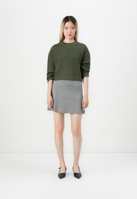 Trui: olijfgroen, getextureerd breiwerk; Rok: grijs, strak, boven de knie; Schoenen: zwart, spitse neus, lage hak. Minimalistisch ontwerp.