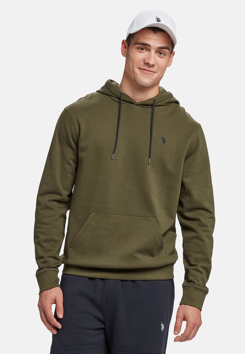 Oliven grøn hættetrøje med snore, kengurulomme og lille logo på brystet. Model iført navy sweatpants og en hvid kasket.