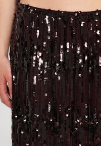 Bordowa spódnica z cekinami z pionowymi rzędami błyszczących cekinów i gładką fakturą; posiada elastyczny pas dla wygody.