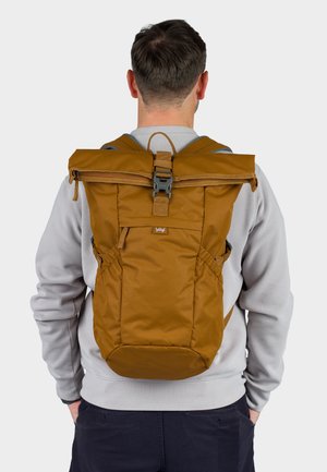 Brązowy plecak typu roll-top z regulowanymi paskami, bocznymi kieszeniami oraz solidnym zapięciem. Gładka tekstura materiału, minimalistyczny design, odpowiedni do różnych zastosowań.