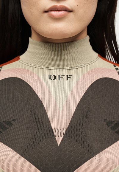 Κοντινό πλάνο του κάτω μέρους του προσώπου και του λαιμού ενός ατόμου που φοράει μπλουζάκι με ψηλό λαιμό και σχέδια, με τη λέξη "OFF" τυπωμένη επάνω.