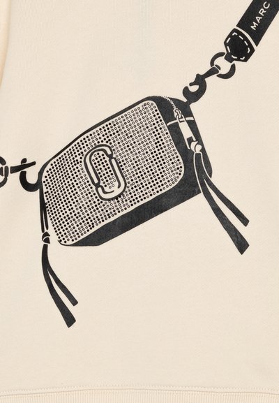 Czarna grafika torby crossbody z perforowaną teksturą, z centralnym logo i frędzlami, wydrukowana na kremowym tle.