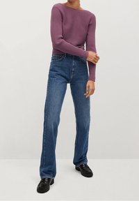 Maglietta a maniche lunghe viola a coste abbinata a jeans blu a vita alta con gamba dritta e mocassini neri, mostrata su uno sfondo neutro.