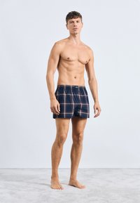 Boxer da uomo a quadri in cotone di colore blu marine, con righe rosse e verdi, vita elastica e vestibilità comoda.