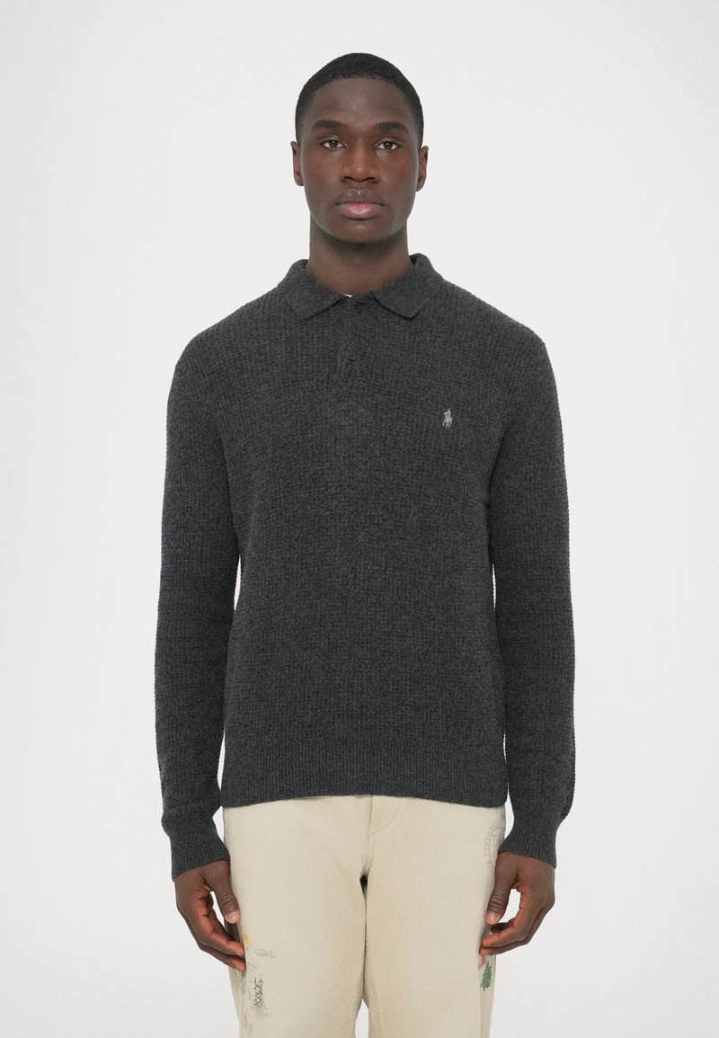 Szürke kötött pulóver galléros, hosszú ujjú és bordázott mandzsettákkal. A mellrészen kis hímzett logóval díszítve.