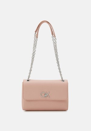 Blush-pinke Lederhandtasche mit silberner Kettenriemen und silbernem "CK"-Logo auf der Vorderklappe vor einfachem weißem Hintergrund.