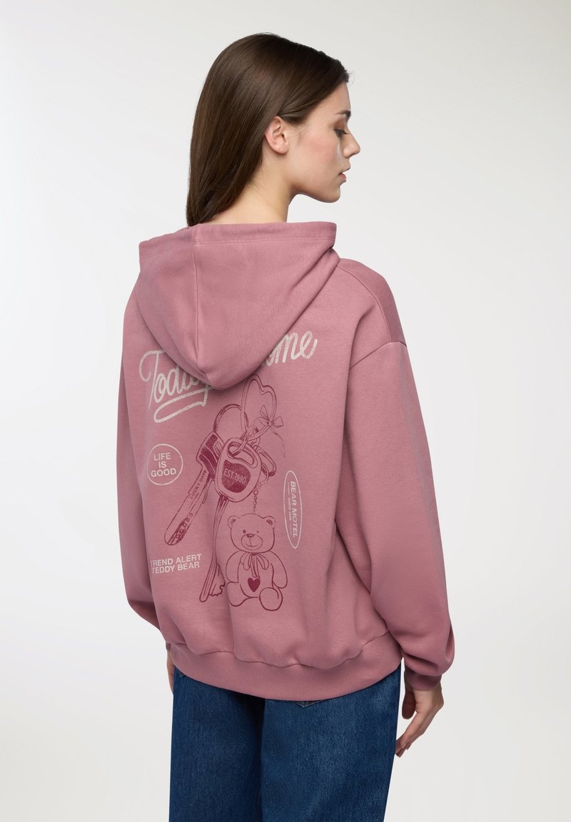 Felpa rosa con stampa grafica sul retro, raffigurante chiavi in stile cartoon e un orsacchiotto. Realizzata in materiale morbido con una vestibilità comoda.