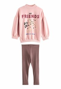 Felpa rosa con maniche a sbuffo, presenta una grafica di un gatto con i puntini e del testo. Leggings marroni a coste. Tessuto casual e morbido.