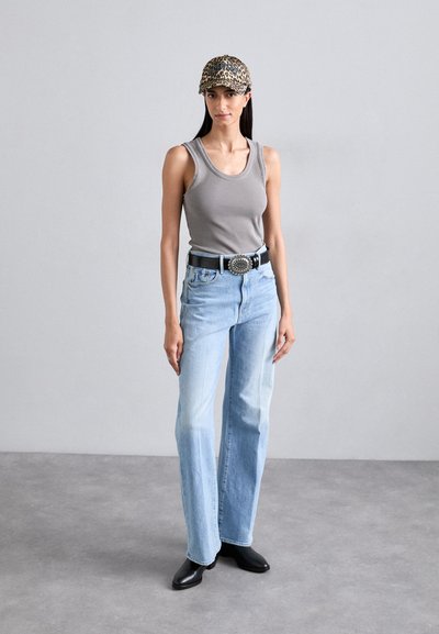 Gray ribbed tank top, blue high-waisted jeans, black belt with silver hardware, and a leopard print cap. Black ankle boots complete the look.