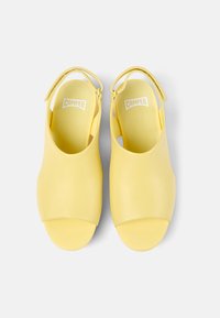 Sandali in pelle gialla con punte aperte, design slingback e forma minimalista. Texture liscia con logo "Camper" in rilievo sulle sole interne.