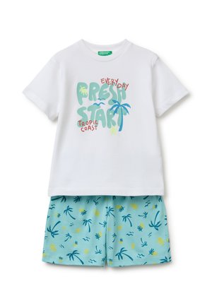 Chemise blanche à manches courtes avec le texte « Everyday Fresh Start Tropic Coast » et un motif palmier, associée à un short bleu clair à imprimé tropical.