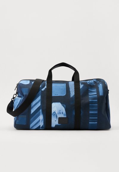 Geantă tip duffle din țesătură albastră, cu un design grafic ce include diverse modele, mânere groase negre și o curea de umăr ajustabilă.