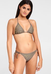 Bikini set in olijfgroen met gouden accenten. Driehoekstop en verstelbare taillesluiting aan de zijkanten. Gladde textuur met uitsnijdingen in de stof.
